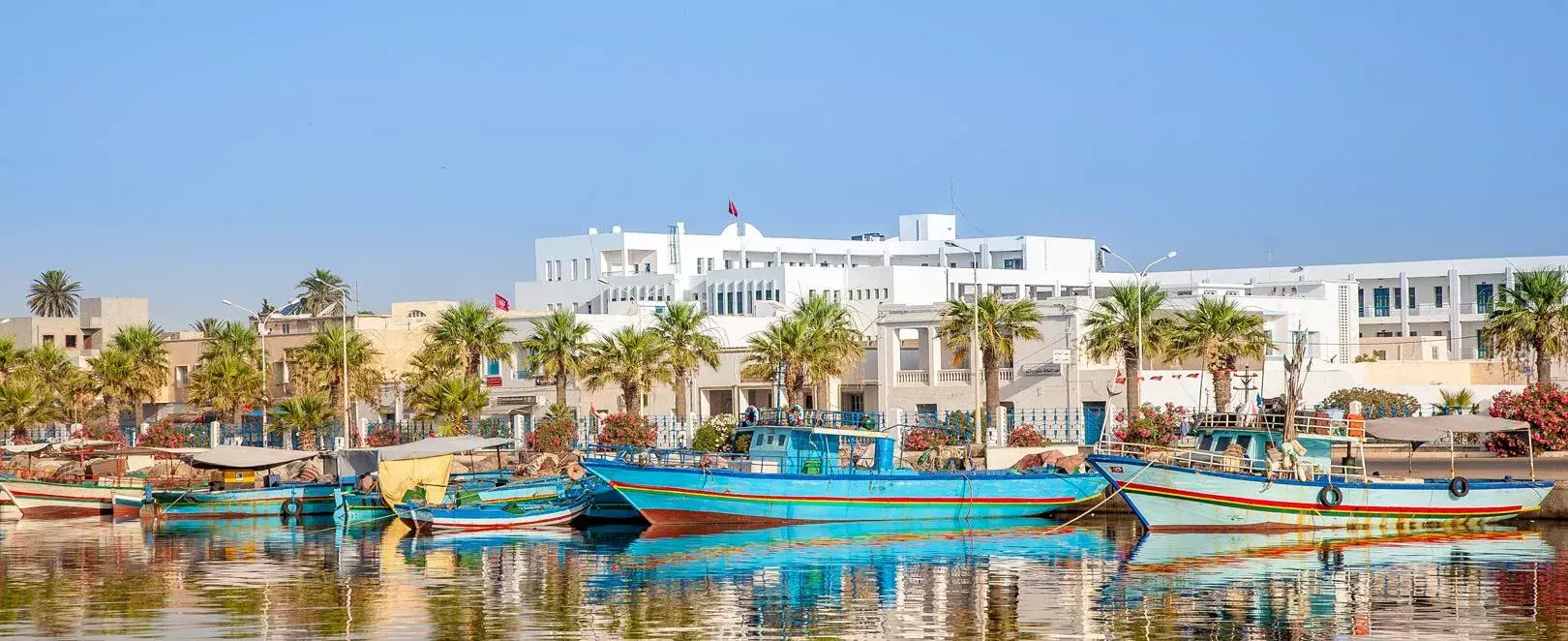 Vue de Hammamet, station balnéaire de Tunisie avec plages, médina blanche et mer turquoise sous le soleil méditerranéen, barques en bois
