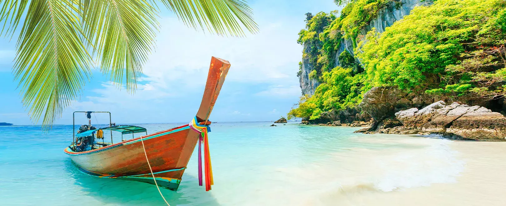 barque en bois traditionnelle thailandaise sur mer turquoise avec palmiers