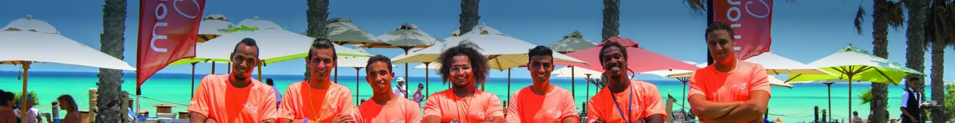 Équipe d'animateurs posant devant des bannières Mondi Club sur la plage