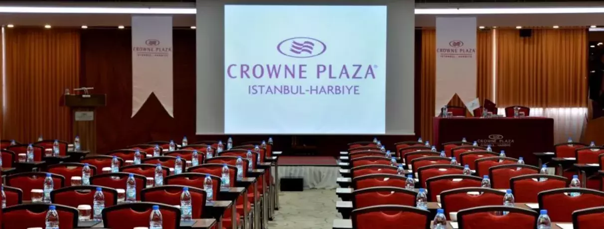 Une salle de conférence avec des chaises alignées et un écran