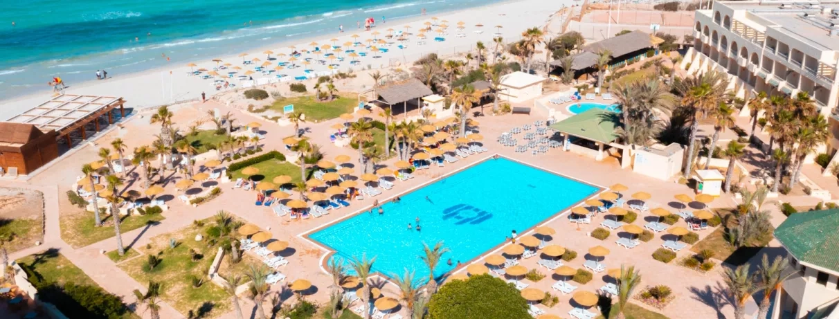 Vue aérienne de la piscine bleue et des jardins fleuris de l'hôtel Vincci Dar Midoun à Djerba.