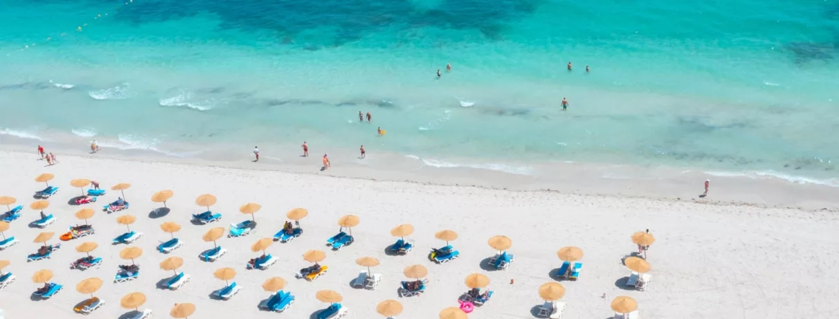 Plage paradisiaque de l'hôtel Vincci Dar Midoun à Djerba avec parasols en paille et eaux cristallines.