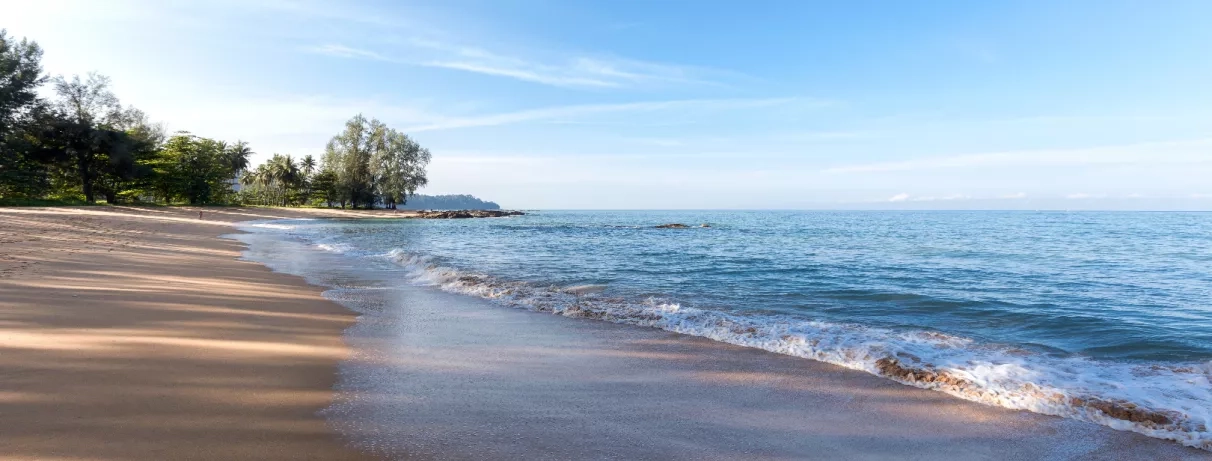 Une vue paisible d'une plage de sable fin bordée par une mer aux reflets turquoise.
