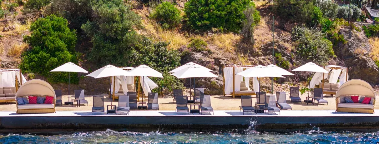 piscine avec des transats, des parasols et des lits