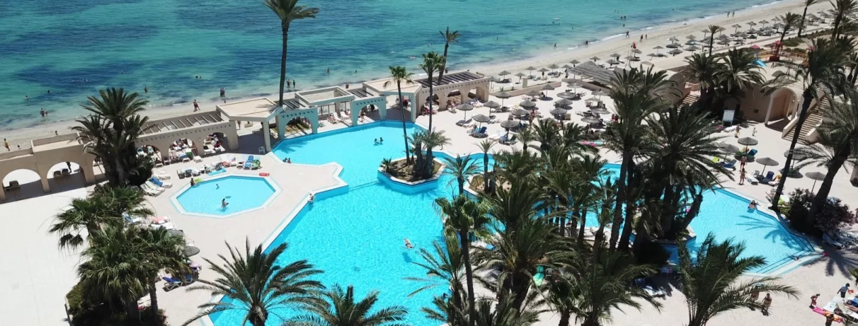 Vue aérienne des piscines extérieures et de la plage privée du complexe hôtelier à Djerba, Tunisie.