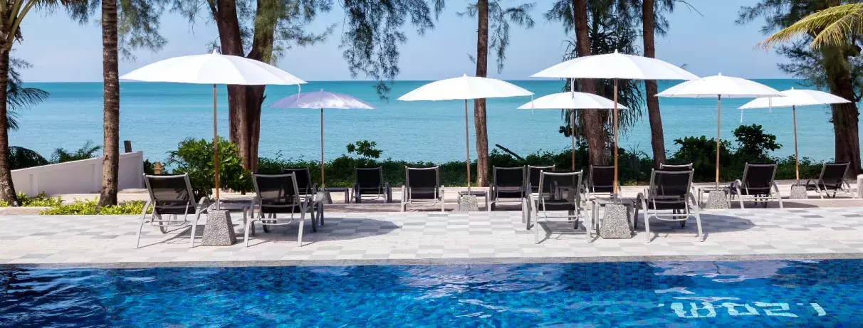 piscine extérieur avec transats et parasols et vue mer en fond