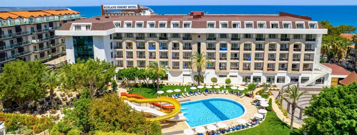 Vue de l'hôtel avec sa grande piscine et ses toboggans et son côté jardin. 