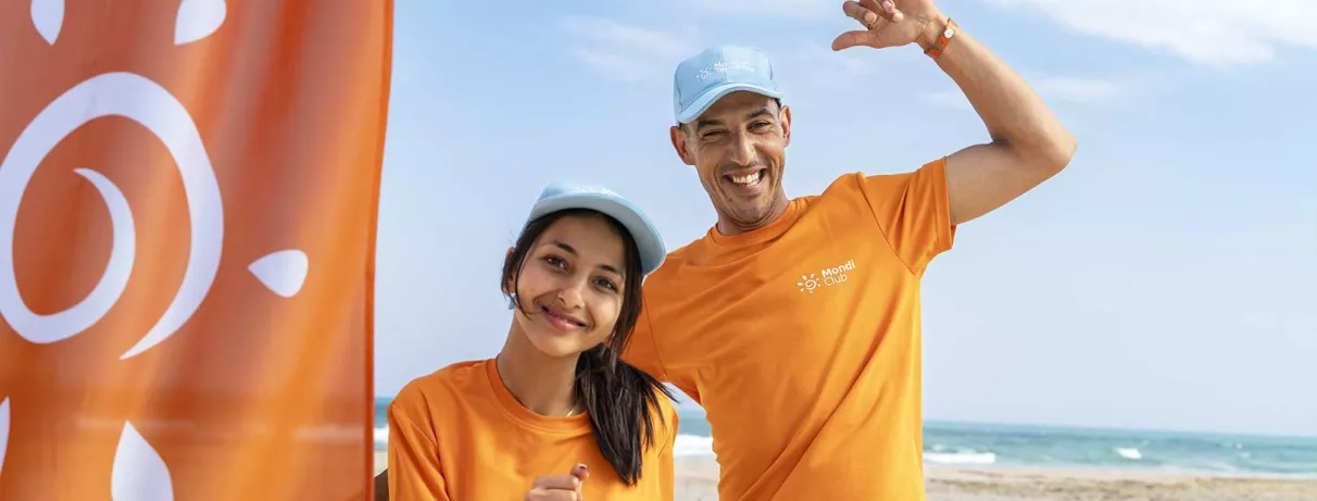 2 animateurs à la plage a côté d'un drapeau Mondi Club