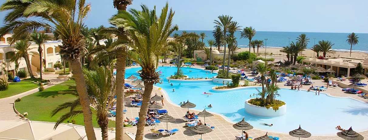 Grande piscine lagon et palmiers à l'hôtel Zephir Djerba en bord de mer Méditerranée, Tunisie.