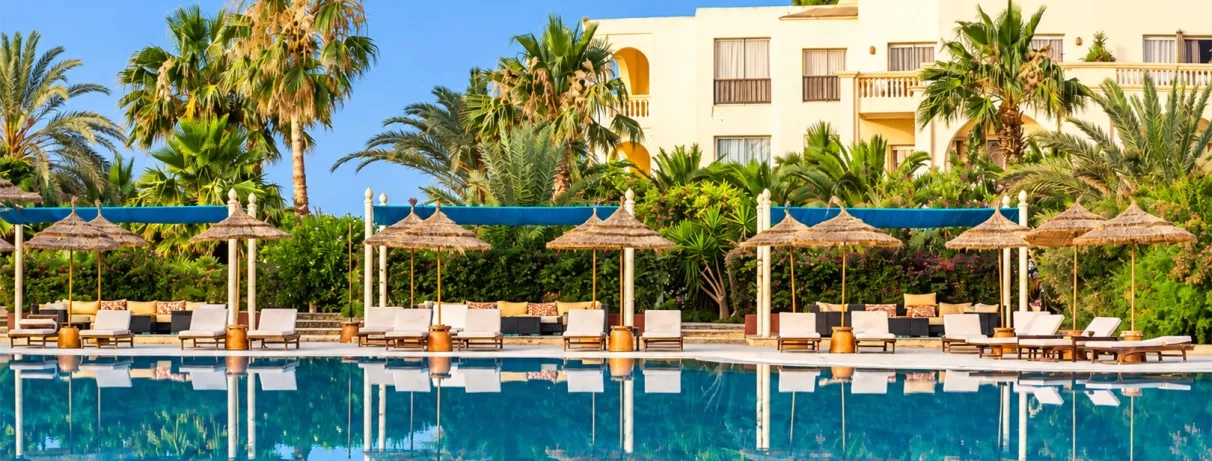 Piscine bordée de palmiers et transats ombragés, ambiance paisible et estivale