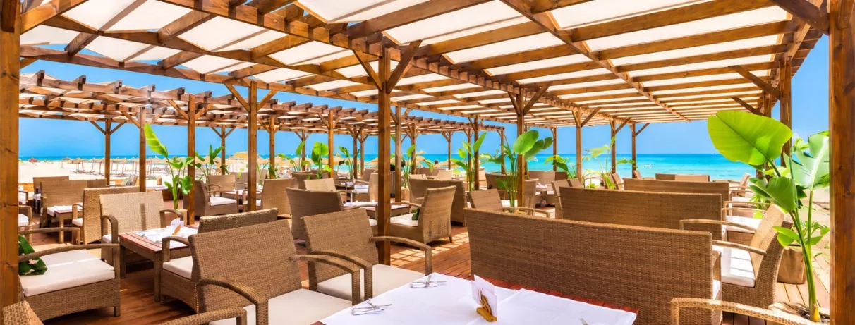 Restaurant en bord de mer, terrasse ombragée avec mobilier en rotin élégant