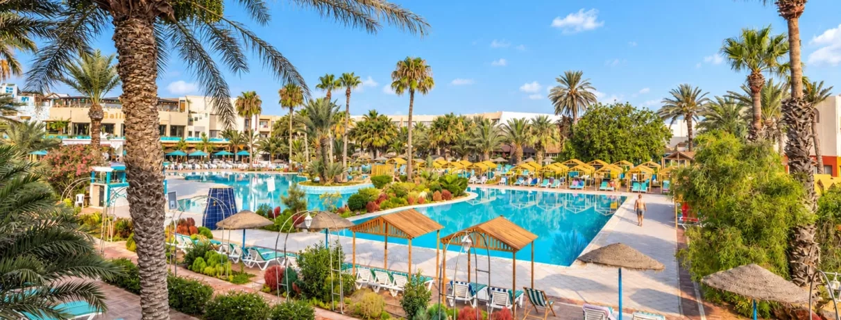Grande piscine extérieure avec transats et palmiers à l'hôtel tout inclus Mondi Club Welcome Meridiana Djerba