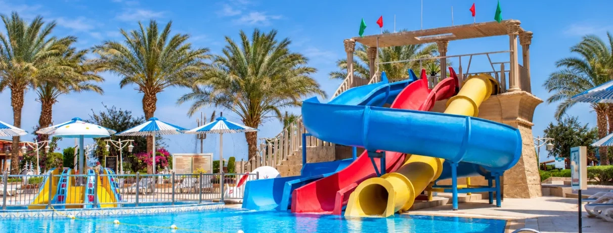 Piscine avec toboggans colorés et palmiers au AMC Royal à Hurghada en Egypte