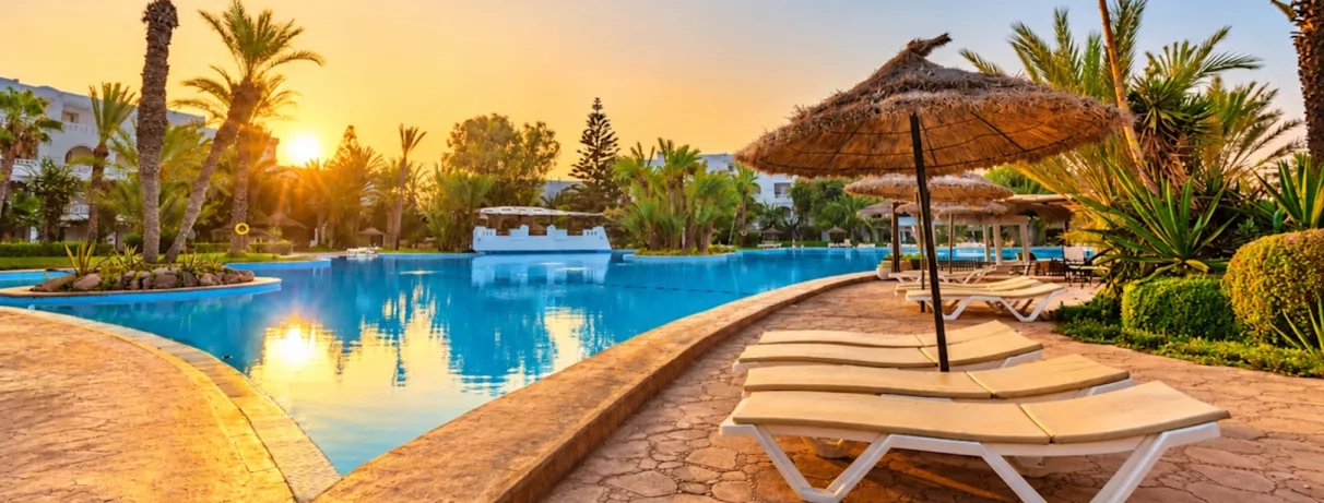 Espace de baignade luxueux avec îlots de palmiers au Djerba Resort, destination de vacances en Tunisie.