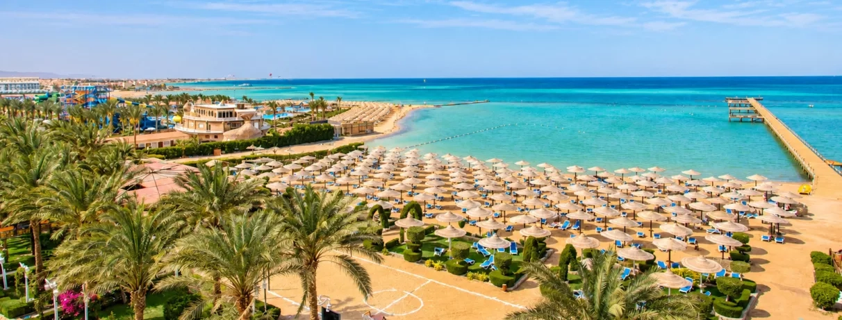 vue aérienne sur la plage avec mer turquoise palmiers et transats au AMC Royal à Hurghada en Egypte
