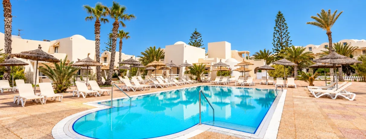 Piscine de détente entourée de transats et parasols en paille au César Thalasso, séjour balnéaire Djerba.
