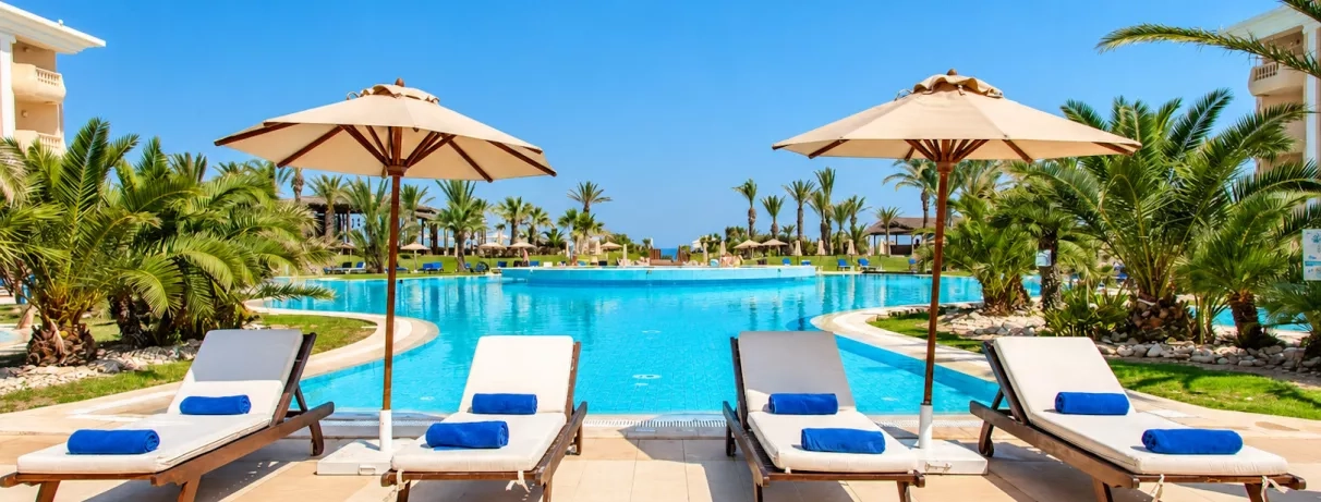 Transats avec serviettes bleues alignés devant la piscine du complexe hôtelier Royal Thalassa à Monastir.