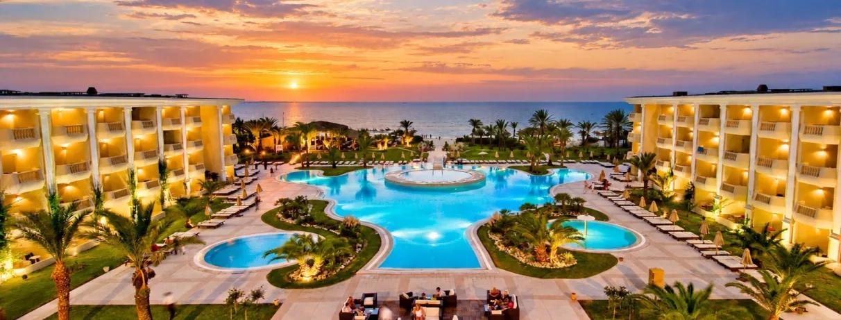 Vue nocturne illuminée des piscines et façades de l'hôtel luxe Royal Thalassa Monastir face mer.