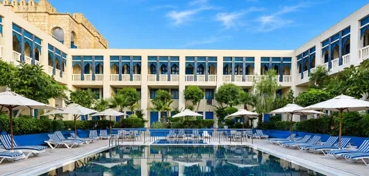 piscine extérieure équipée de transats et bâtiment de l'hôtel