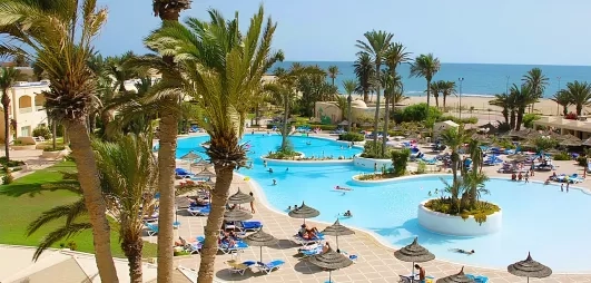 Grande piscine lagon et palmiers à l'hôtel Zephir Djerba en bord de mer Méditerranée, Tunisie.