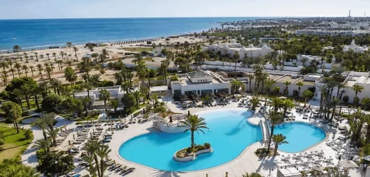 Une vue d'ensemble de l'hôtel, entre piscine à débordement, jardins luxuriants et plage privée, en bordure de mer.