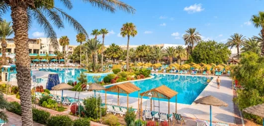 Grande piscine extérieure avec transats et palmiers à l'hôtel tout inclus Mondi Club Welcome Meridiana Djerba