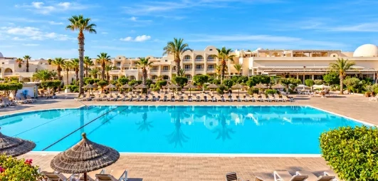vue de la piscine avec palmiers et façade de l'hôtel du Djerba Aqua Resort à Djerba en Tunisie