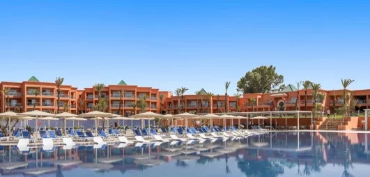 Vue Générale sur la piscine extérieure avec des transats au bord de la piscine et un salon marocain à toit couvert  