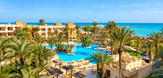 Vue panoramique sur les jardins, la piscine bleue et la plage méditerranéenne du complexe touristique Safira Palms Djerba.