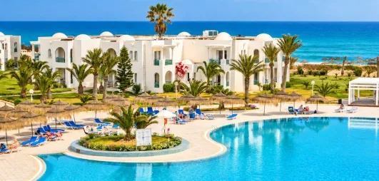 Jardin luxuriant et piscines du complexe hôtelier en bord de mer Méditerranée pour des vacances en Tunisie.