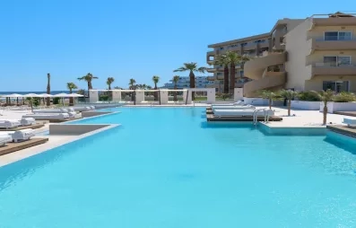 Grande piscine de l'hôtel, bâtiment, transats, parasol, ciel bleu