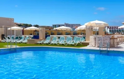 Une piscine d'un bleu éclatant entourée de parasols blancs et de bâtiments élégants sous un ciel radieux.