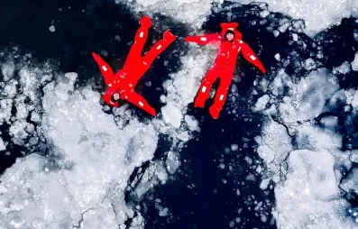 Vue aérienne, combinaisons rouges flottant sur glace fragmentée.