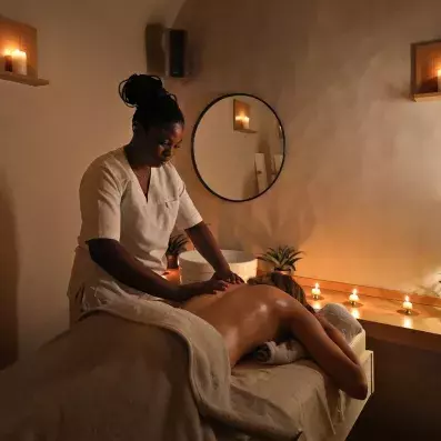 Séance de massage bien‑être dans un spa avec ambiance tamisée et bougies allumées.