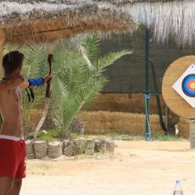 Séance de tir à l’arc en plein air avec cible colorée et cadre tropical.
