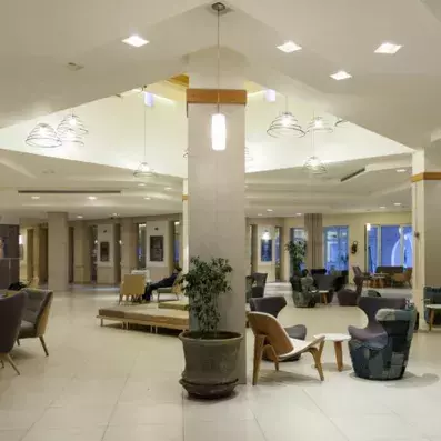 Lobby d’hôtel spacieux avec fauteuils contemporains, éclairage design et colonnes décoratives.”