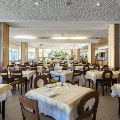 Salle de restaurant spacieuse avec tables dressées, buffet central et ambiance lumineuse.