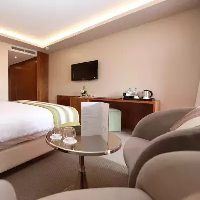 Chambre avecgrand lit de deux places, TV accroché et deux chaises avec table d'appoint