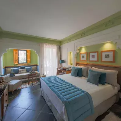 Chambre verte lumineuse avec un lit double et un coin salon.