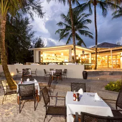 restaurant sur la plage avec des palmiers et l'hôtel en fond