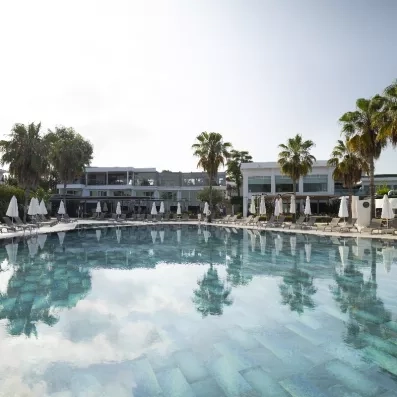 Une vaste piscine entourée de nombreux transats et parasols blancs.