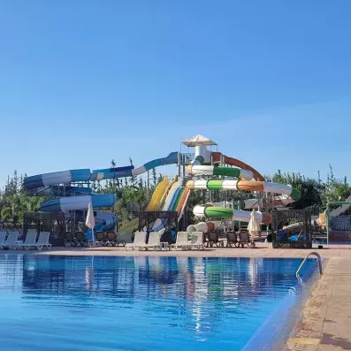 vue sur la piscine en premier plan et au fond des toboggans colorés 