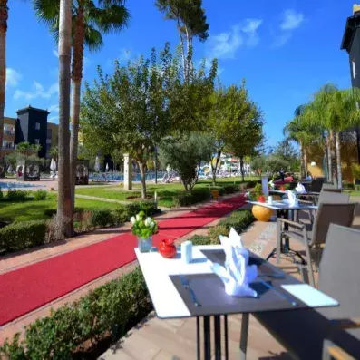 café  extérieur dans une terrasse séparé par une allée et au fond un jardin et la piscine