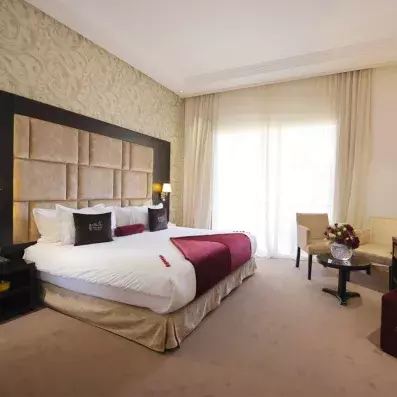 lit double lit double avec une tête de lit en tissu et en bois marron et juste à côté une fenêtre 