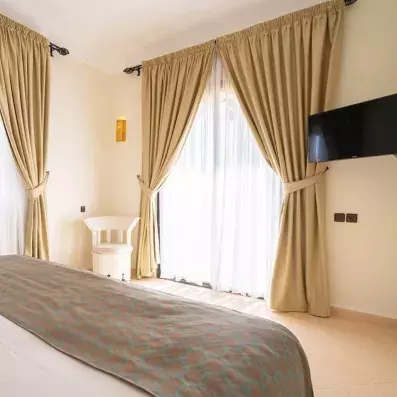 lit double avec deux fenêtres et une télévision en face du lit