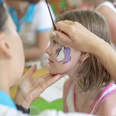 enfant se faisant maquillé par des animateurs