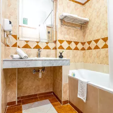 Salle de bains de l'hôtel avec baignoire et vasque intégré en marbre avec miroir
