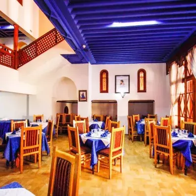Salle restaurant de l'hôtel avec un plafond en bois bleu, tables et chaises 