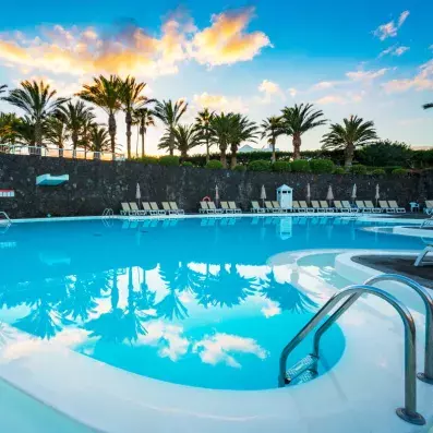 piscine extérieure avec palmiers et coucher du soleil