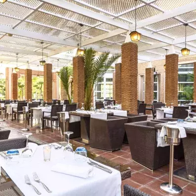 restaurant extérieur de l'hôtel avec table et chaise sur la terrasse avec de la verdure autour